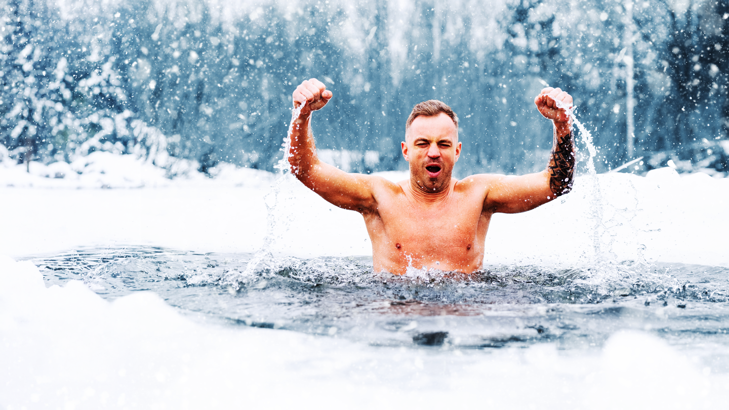 Jubelnder Mann beim Eisbaden in einem zugefrorenen See im Schneefall